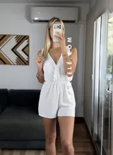 Mono corto negro con escote en V cruzado, sin mangas y con cinturón dorado.