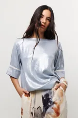 Blusa de manga corta con brillo, color celeste metalizado, con puños anchos ribeteados en color crema.