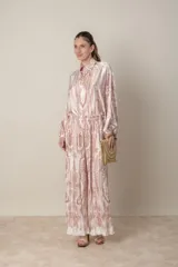 Pantalon palazzo de corte amplio y fluido, confeccionado en tela plisada con estampado estilo paisley en tonos beige y rosado. Presenta cintura elastizada y un diseño ligero ideal para climas cálidos.