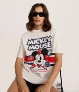 Remera blanca de algodón con estampado gráfico de Mickey Mouse en el centro, rodeado de estrellas y franjas rojas y azules. Incluye el texto "MICKEY MOUSE" en la parte superior.