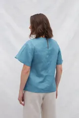 Blusa blanca de lino con escote en V y mangas cortas amplias.