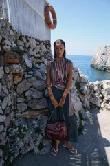 Bolso tipo shopper color borravino con diseño acolchado y pespuntes en rombos. Cuenta con solapa frontal y una correa de hombro que combina material sintético con una cadena metálica dorada.