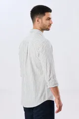 Camisa de manga larga de lino y algodón, con diseño de rayas verticales en tonos celestes y blancos. Presenta cuello camisero, cierre frontal con botones y pequeño bordado al tono en el pecho.