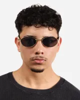 Lentes de sol ovalados con marco dorado y lentes oscuros.