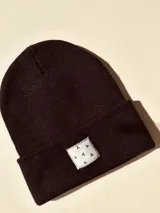 Gorro de lana color lila con etiqueta cuadrada blanca con diseño de triángulos negros.