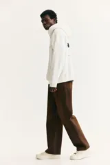 Canguro blanco de mezcla de algodón con interior cepillado suave y estampado frontal negro con la palabra "Recordin'". Tiene capucha de doble capa con cordón ajustable, hombros caídos, bolsillo canguro y puños y bajo acanalados. Corte holgado.