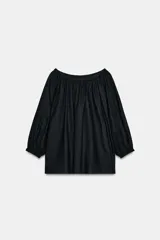 Blusa negra de manga larga con escote recto fruncido (hombros descubiertos) y mangas abullonadas terminadas en elástico.