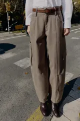Pantalón cargo de tiro alto color marrón topo, con pierna ancha y holgada que se estrecha hacia el tobillo. Presenta bolsillos delanteros, bolsillo de plastrón lateral y falso bolsillo de vivo en la espalda.
