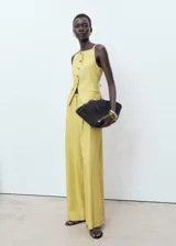 Pantalón de tiro alto color amarillo con sutil diseño de rayas verticales, de corte recto y largo, con bolsillos laterales y cierre frontal de botón y cremallera.