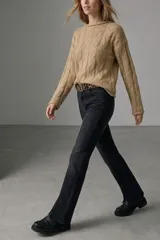 Sweater de punto color visón con diseño de trenzas verticales, cuello redondo y mangas largas.