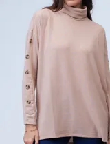 Polera negra de tejido soft con cuello alto y mangas largas con aplique de botones.