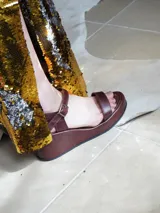Sandalias de cuero marrón con plataforma baja, tira frontal ancha y tira ajustable con hebilla en el talón.