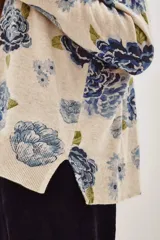 Sweater de punto con diseño estampado de flores en tonos azules y verdes sobre base color crema. Presenta cuello redondo y mangas largas con corte holgado.