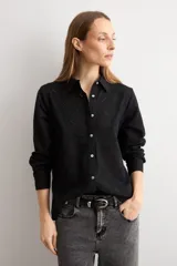 Camisa blanca de manga larga con frente de tela broderie con diseño de rombos calados y espalda lisa. Presenta cuello clásico y cierre frontal con botones.