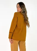 Sweater de punto azul marino con cuello en V, mangas largas con puños acanalados y detalle de línea en color marrón en el cuello y puños. Presenta un pequeño aplique decorativo en la parte inferior.