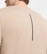 Remera deportiva de hombre con tecnología dry fit, cuello redondo y manga corta. Presenta un diseño liso en color beige con una pequeña etiqueta decorativa en el dobladillo.