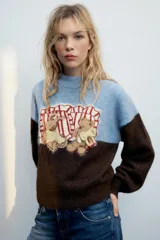 Jersey de punto con cuello redondo y manga larga, de diseño combinado en color celeste en la parte superior y marrón en la inferior y las mangas. Cuenta con un diseño estampado de ositos en el frente.