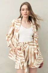 Blazer negro con estampado de hojas orgánicas en blanco, corte recto, solapas clásicas y bolsillos con tapa.