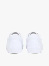 Zapatillas Tommy Hilfiger modelo Lulu Gold, de color blanco y diseño de corte bajo. Están confeccionadas en capellada sintética con cordones blancos, ojetes metálicos dorados y forro interno de algodón. Presentan detalles distintivos de la marca y monograma TH en el lateral.