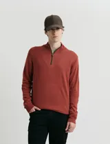 Sweater de punto color verde oliva, con cuello alto y medio cierre frontal. Presenta coderas en símil nappa y puños acanalados.