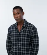 Camisa de pijama de manga larga con cuello camisero y cierre frontal de botones. Presenta un estampado de cuadros y está confeccionada en tejido de punto de algodón.