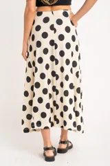 Falda midi color crudo con estampado de lunares negros, corte evasé y cintura alta.