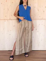 Pantalón de lino color beige con rayas verticales negras y tajos laterales.