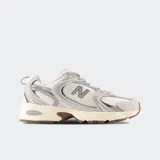 Championes New Balance modelo 530, de estilo retro, en color gris claro con detalles blancos y suela marrón. Combinan malla transpirable y refuerzos sintéticos con tecnología de amortiguación ABZORB.