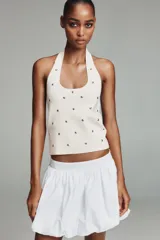 Top de punto negro con cuello halter y escote redondo, decorado con tachas metálicas plateadas distribuidas por toda la prenda.