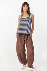 Musculosa de corte holgado con diseño a rayas horizontales en tonos marrón y crudo. Presenta ribetes en color fucsia en el cuello redondo y en las sisas, además de un pequeño bordado decorativo en el centro del pecho.