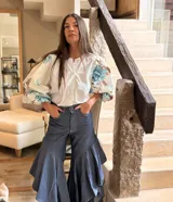 Camisa de popelina con cuerpo central blanco y mangas abullonadas con estampado floral en tonos celestes y marrones, cuello redondo y cierre frontal de botones.
