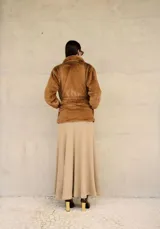 Campera de piel sintética en color tostado, con solapas amplias, mangas largas y corte recto. Su diseño de textura suave y envolvente ofrece un acabado elegante y cálido.