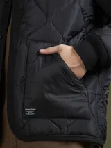 Campera acolchada verde militar con cuello mao, cierre frontal con botones a presión y bolsillos laterales.