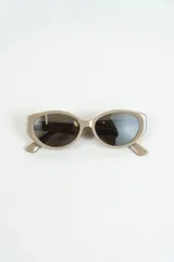 Lentes de sol color beige con forma cat-eye.