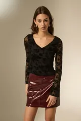 Top de manga larga con cuello en V, confeccionado en tela de tul con estampado floral aterciopelado en color negro.