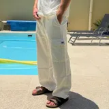 Pantalon cargo de lino color blanco, de corte holgado y diseño relajado. Cuenta con bolsillos laterales tipo cargo con solapa y cierre de cordón en la cintura.