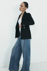 Blazer cruzado color beige, de manga larga, con cuello solapa y forro interior negro. Presenta cierre frontal con botones dorados y bolsillos de vivo en el pecho y bolsillos con solapa en el delantero.