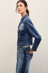 Saco de denim azul con efecto deslavado, corte entallado, cuello mao, mangas largas y cierre frontal con botones metálicos. Cuenta con bolsillos frontales appliquéd y un diseño de costuras estructuradas con dobladillo en punta.