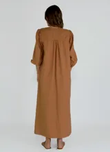 Vestido largo color beige con escote en V, mangas 3/4 abullonadas y corte holgado.