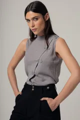 Top sin mangas de tejido de punto fino con acabado brillante, cuello alto y cierre frontal decorativo con nudos estilo oriental.