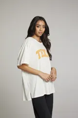 Remera color crema de corte holgado con estampado de la palabra "TEXAS" en color naranja.