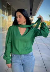 Blusa de satén color verde, con cuello en V y detalle de lazo integrado al cuello. Presenta mangas largas abullonadas con puños ajustados.