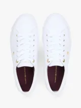Zapatillas Tommy Hilfiger modelo Lulu Gold, de color blanco y diseño de corte bajo. Están confeccionadas en capellada sintética con cordones blancos, ojetes metálicos dorados y forro interno de algodón. Presentan detalles distintivos de la marca y monograma TH en el lateral.