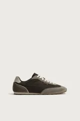 Zapatillas de estilo retro con cordones blancos, capellada marrón combinada con paneles de gamuza gris y detalles en cuero. Suela de goma a contraste.