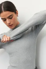 Polera de tejido de punto acanalado en color crema, con cuello alto y manga larga, de ajuste ceñido al cuerpo.