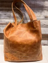 Bolso tipo shopper de cuero con acabado texturizado en tono metalizado claro. Cuenta con doble asa de hombro y etiqueta de cuero con logo grabado en la parte inferior frontal.