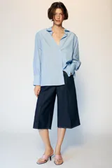 Camisa de manga larga con cuello solapa y hombreras. Presenta un diseño de rayas verticales en tonos azul y blanco, con cierre frontal de botones y puños anchos.