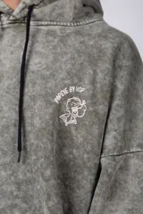 Buzo canguro oversize de algodón friza con efecto de teñido artesanal desgastado. Presenta capucha con cordones negros, bolsillo frontal tipo canguro y estampa pequeña de Popeye en el pecho.
