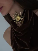 Collar compuesto por una tira de cuero y un dije grande en forma de sol de bronce.