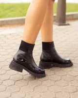 Botas negras de cuero, hechas a mano, con suela track y detalle de costura en la puntera.